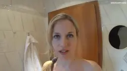 Nackte blonde Mia lächelt frech in Badezimmer mit blanken Brüsten