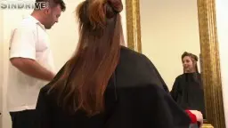 Antonia lächelt im Friseurstuhl, während der Mann hinter ihr mit der Schere spielt