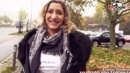 Lächelnde mollige Blondine mit lockigem Haar und Schal steht outdoors auf einem Parkplatz