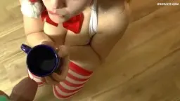 Weihnachtsengel mit Zöpfen kniet nackt am Boden und trinkt Pisse aus blauem Becher
